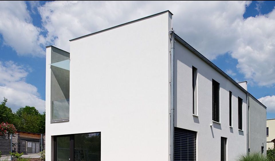 Individuální řešení dřevostavby s bílou kubickou fasádou, rohový pohled