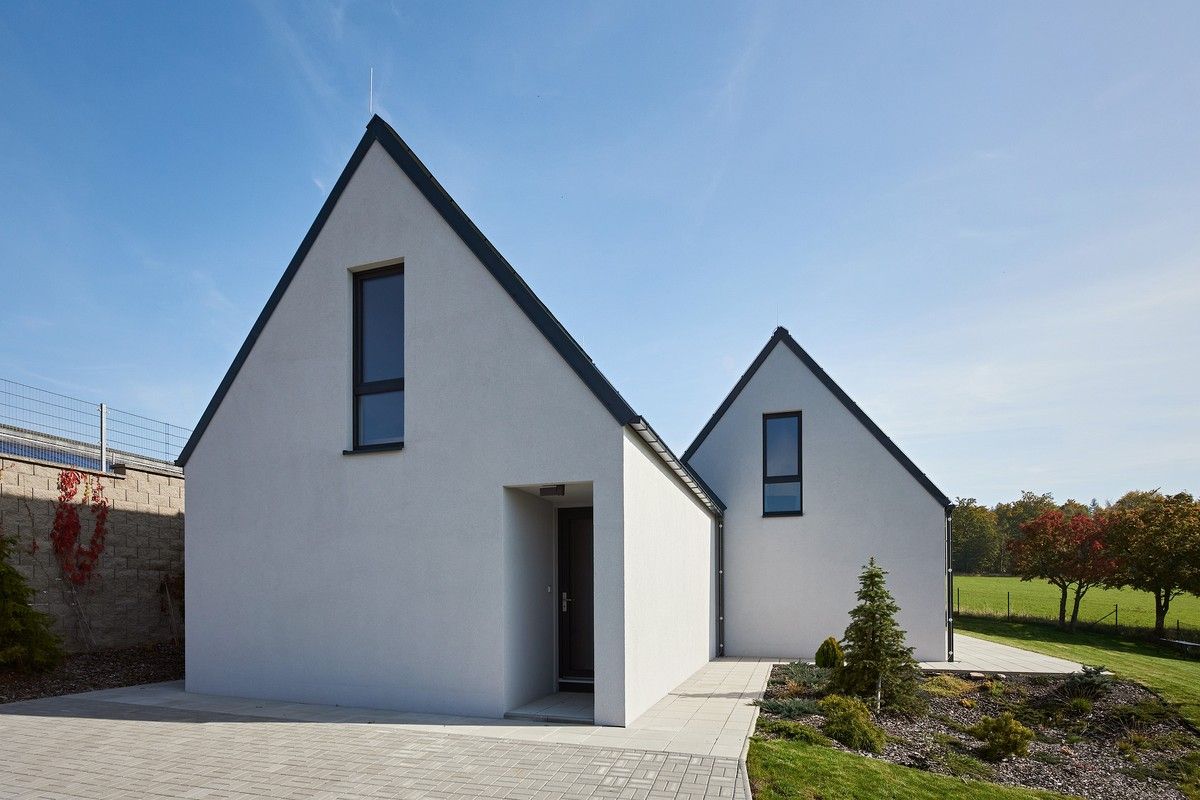 Dvojice dřevostaveb s bílou fasádou a sedlovými střechami
