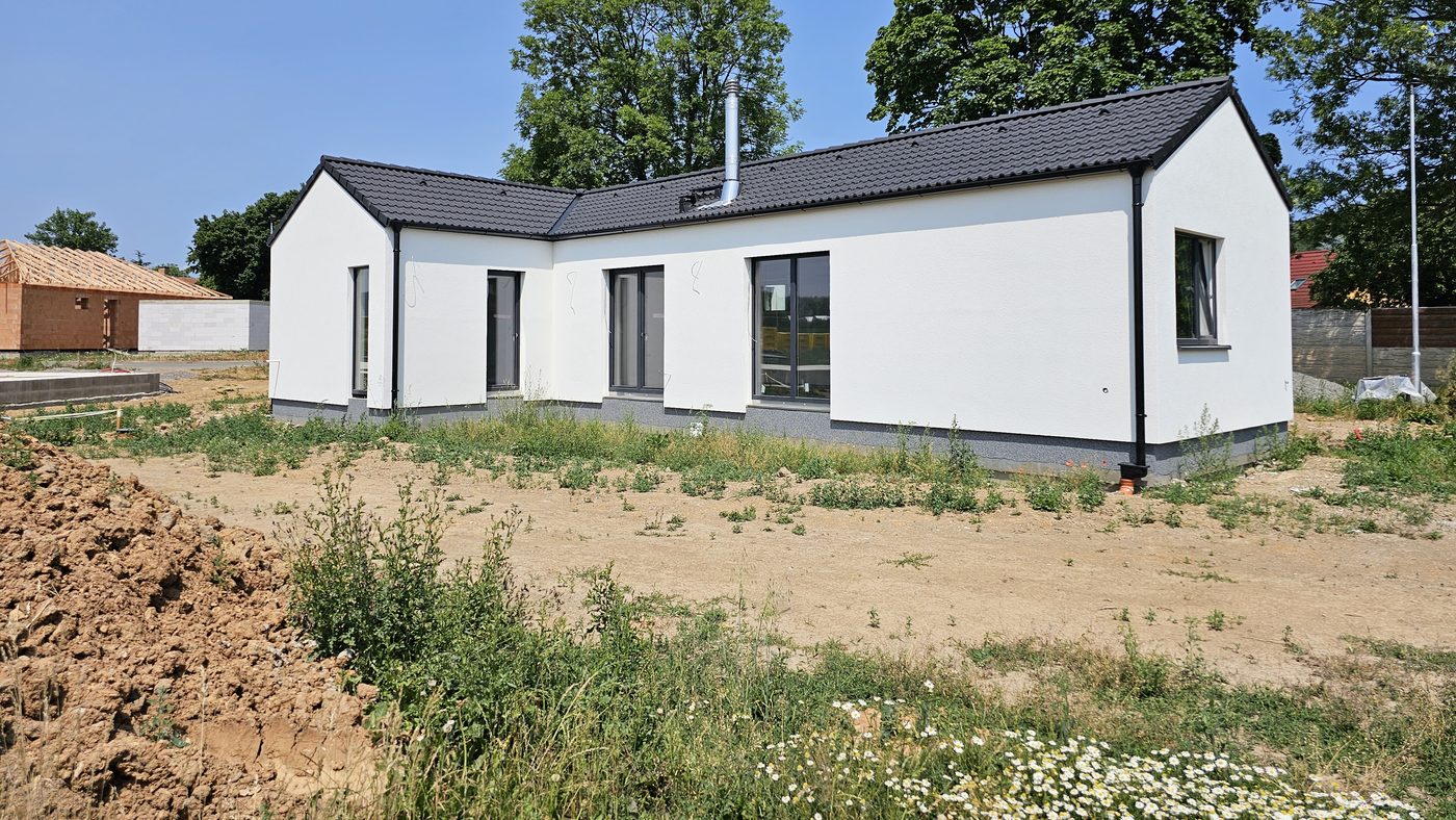 Přízemní dřevostavba s tmavou střechou na čerstvě dokončeném pozemku