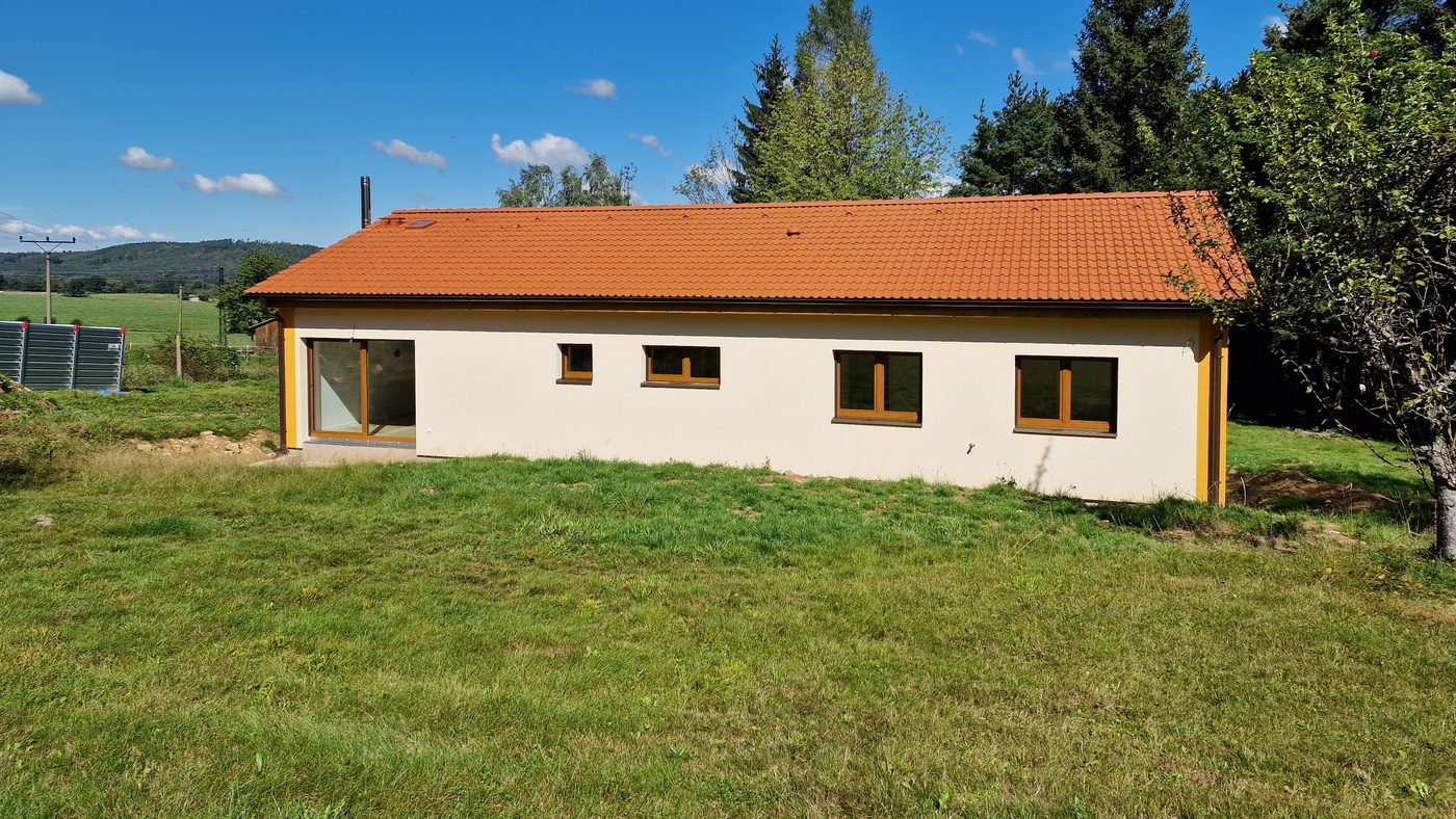 Přízemní dřevostavba s cihlovou střechou na travnatém pozemku